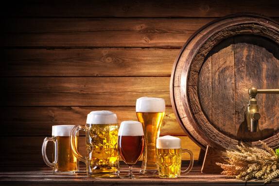 Oktoberfest-Bierfass und Biergläser mit Weizen und Hopfen auf Holztisch